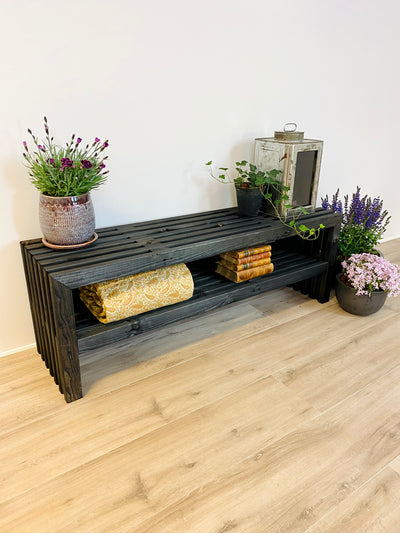 Sort trallebænk med hylde, stylet med potteplanter og lanterne